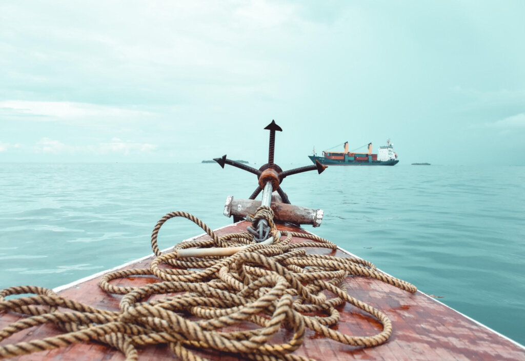 An anchor and rope at the bow of a boat out on the water.